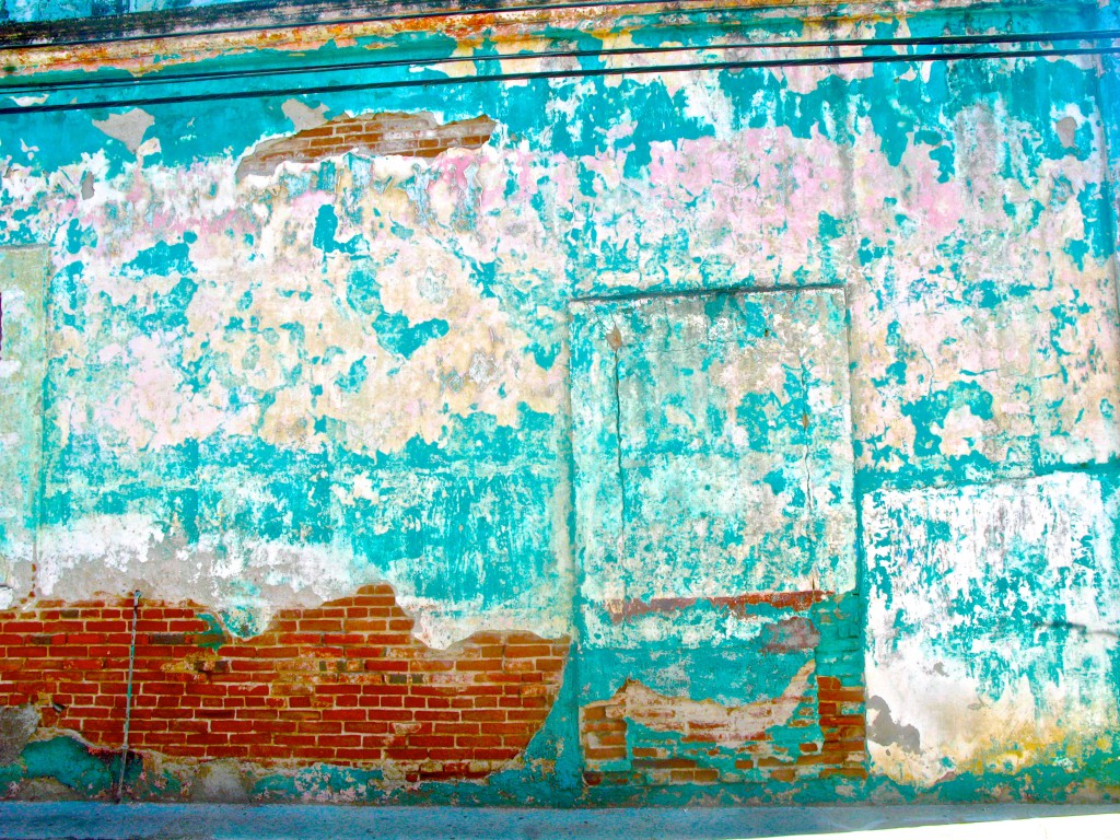 An eroding wall exposing brick and blues, pinks and yellows, demonstrating how urban exploration makes you see things differently. (image © Eva Boynton).