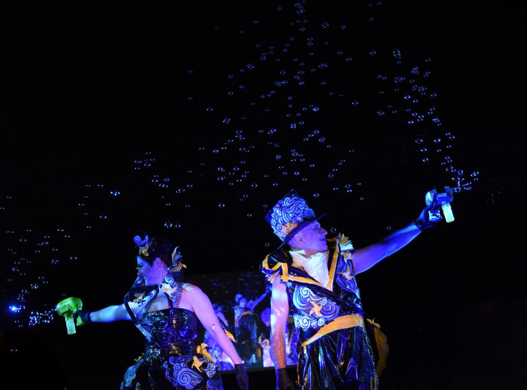 Elaine Gateno and Daniel Munoz in blue costumes with bubbles, a cultural encounter with the Big Sur Fashion Show. (Image © Meredith Mullins.)