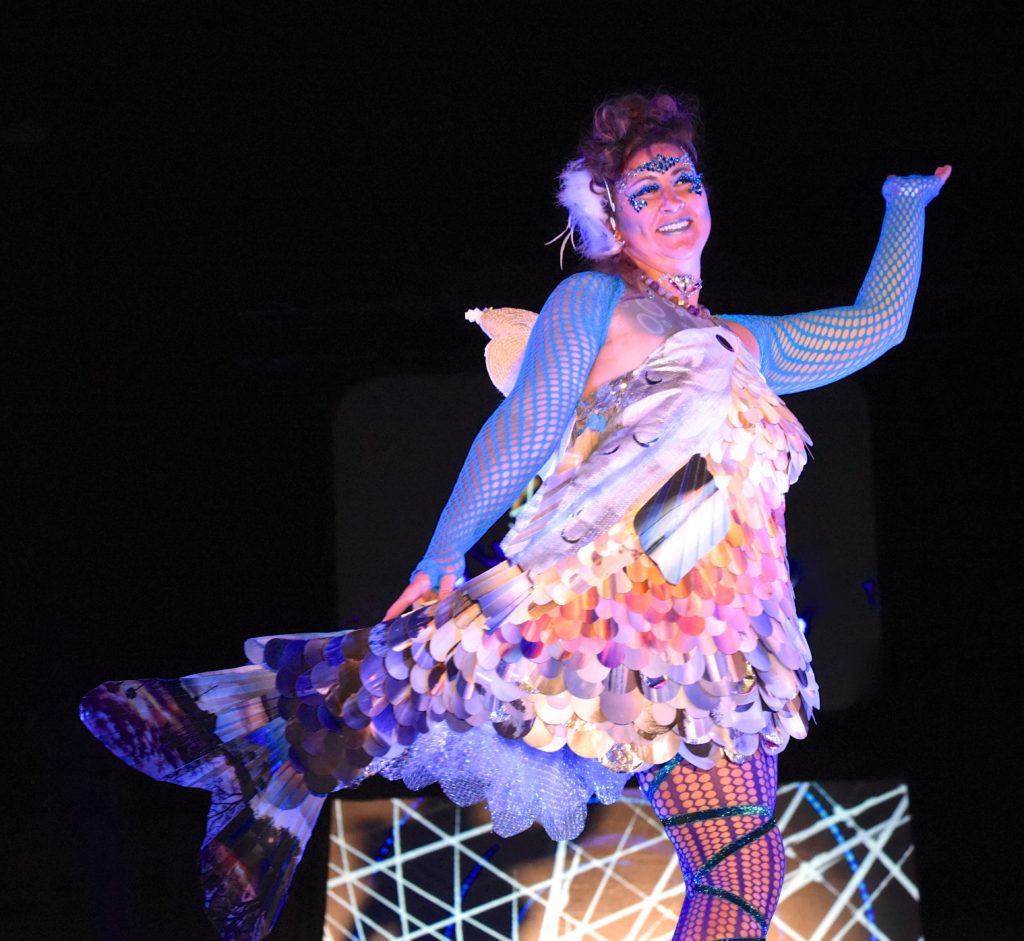 Cassy August dresses in a fish costume made of sunrise photos at the 2018 Big Sur Fashion Show, a cultural encounter with the spirit of community. (Image © Meredith Mullins.)