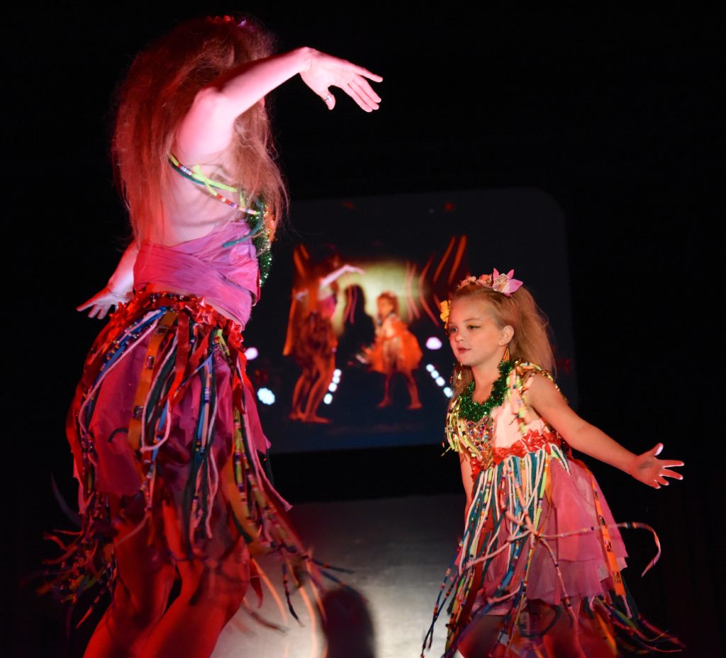 Jamie Oksas and Scarlett Moffat dancing in red outfits at the 2018 Big Sur Fashion Show, a cultural encounter with the spirit of community. (Image © Meredith Mullins.)