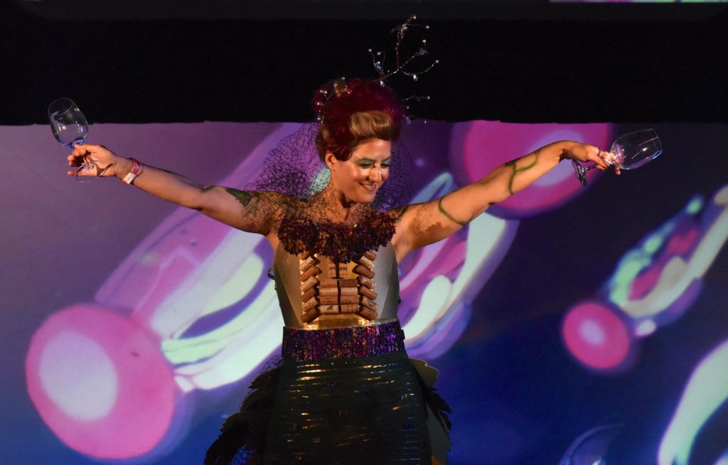 Woman in green dress with wine cork bodice at the 2018 Big Sur Fashion Show, a cultural encounter with the spirit of community. (Image © Meredith Mullins.)