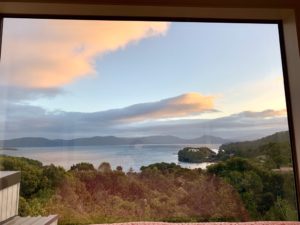 A view of Stewart Island through a window reminds the writer of the cultural tradition of shared sacrifice that sustains a community during lockdown. (Image © Joyce McGreevy)